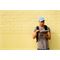 Marcus Perez using the HP Pavilion x360 in Tablet Mode while leaning against a yellow wall (Other)